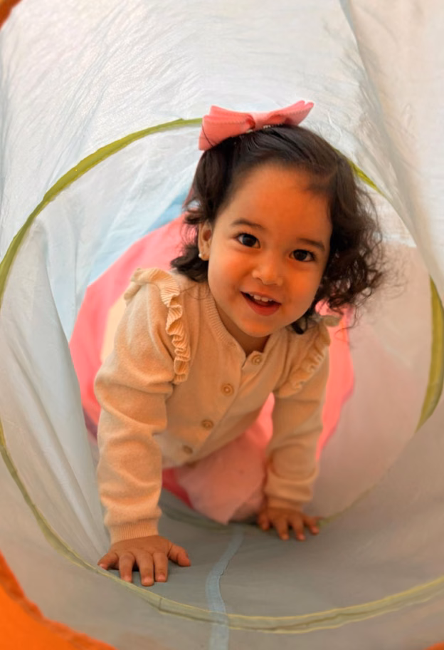 Una pequeña alumna de Tiny Dancers sonríe mientras recorre un túnel de juego